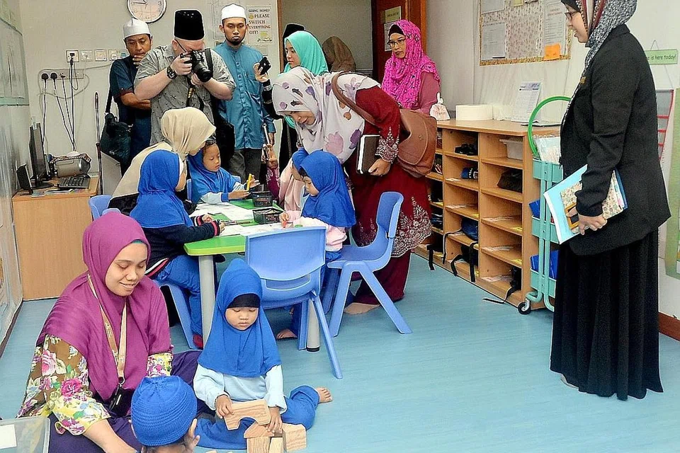 LAWATAN SAMBIL BELAJAR: Peserta rombongan dari Malaysia seperti Cik Rosnah Ahmad (bertudung putih, membongkok), sedang meninjau dan memetik gambar di kelas tadika yang diadakan di Masjid Mujahidin. - Foto-foto KHALID BABA
