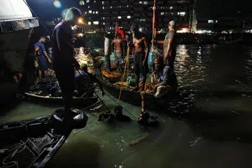 NAHAS BOT KARAM: Anggota pasukan penyelamat menjalankan operasi menyelamat selepas sebuah bot yang membawa 20 penumpang karam di sungai Buringanga dekat Dhaka pada Ahad. 