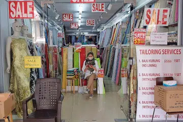 PERNIAGAAN MALAP: Seorang jurujual menunggu pelanggan masuk dan berbelanja di kedai menjual kain di 63, Arab Street. Kedai itu antara beberapa kedai kain di sepanjang jalan itu yang mengadakan jualan murah kerana hendak menghabiskan stok sebelum ditutup. - Foto BH oleh KHALID BABA