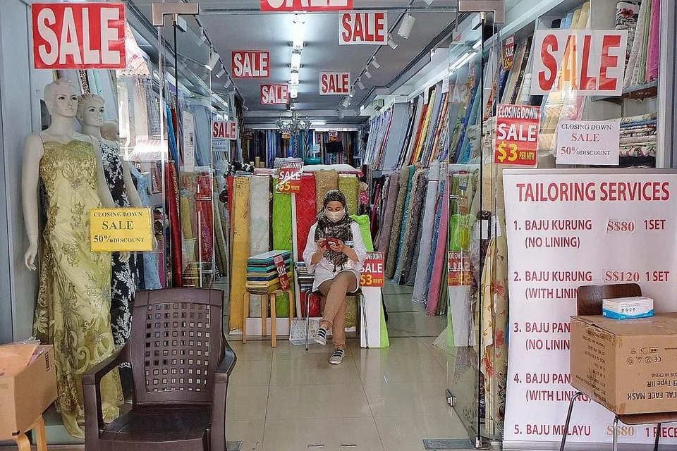 PERNIAGAAN MALAP: Seorang jurujual menunggu pelanggan masuk dan berbelanja di kedai menjual kain di 63, Arab Street. Kedai itu antara beberapa kedai kain di sepanjang jalan itu yang mengadakan jualan murah kerana hendak menghabiskan stok sebelum ditutup. - Foto BH oleh KHALID BABA