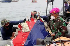 TEMUI SERPIHAN PESAWAT: Pegawai keselamatan Indonesia menunjukkan serpihan pesawat dalam sebuah bot ketika menjalankan operasi mencari dan menyelamat di kawasan perairan dekat Jakarta yang dipercayai lokasi terhempasnya pesawat Sriwijaya Air. - Foto EPA-EFE