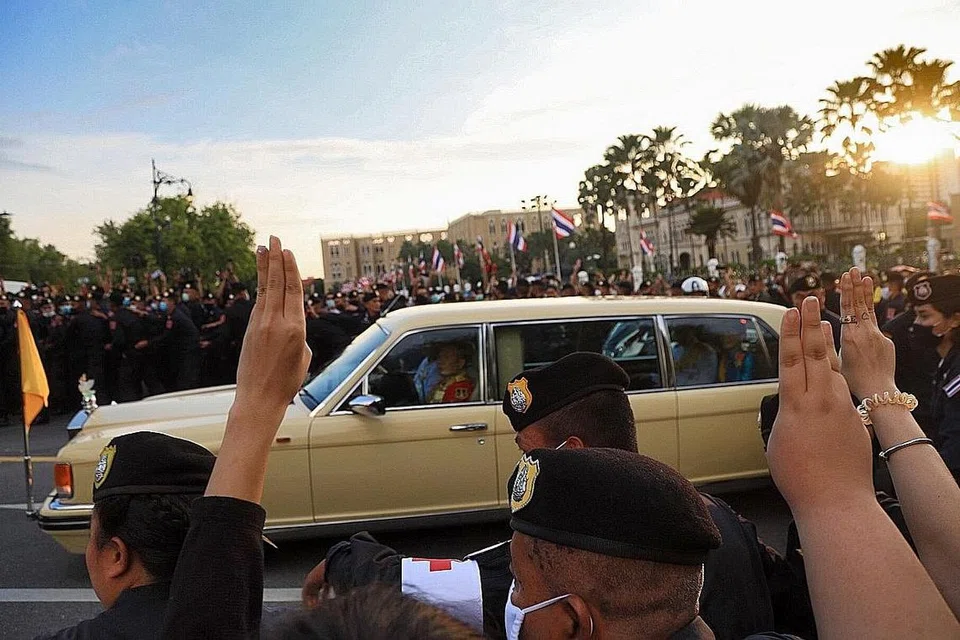 TABIK HORMAT TIGA JARI: Sebahagian penunjuk perasaan memberi tabik hormat tiga jari iaitu satu isyarat penentangan pergerakan demokrasi dan dirakam ketika sebuah kenderaan diraja membawa Permaisuri Suthida melalui sekumpulan para penunjuk perasaan. - Foto EPA-EFE