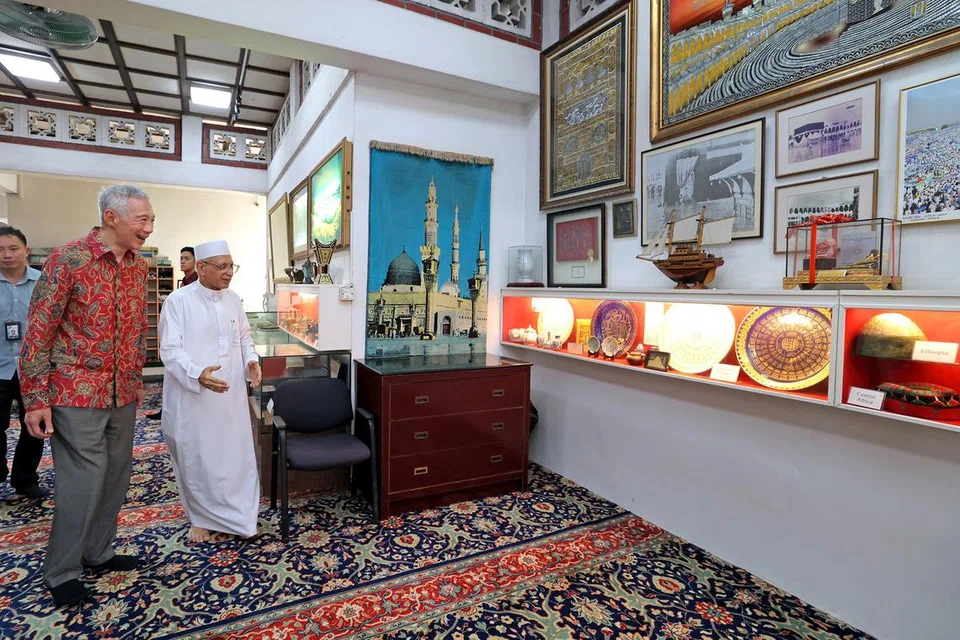 Habib Syed Hassan Syed Mohamed Salim Al-Attas atau lebih dikenali sebagai Habib Hassan (kanan) membawa Menteri Kanan, Encik Lee Hsien Loong, melihat artifak dan karya seni yang dipamerkan di muzium mini Masjid Ba’alwie. 