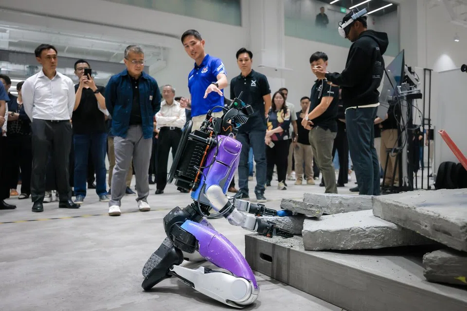 Menteri Undang-Undang merangkap Menteri Kedua Ehwal Dalam Negeri, Encik Edwin Tong (dua dari kiri), memerhatikan robot humanoid beraksi dalam simulasi tapak pascaletupan semasa pelancaran Pusat Robotik Humanoid Home Team (H2RC) pada 30 September.