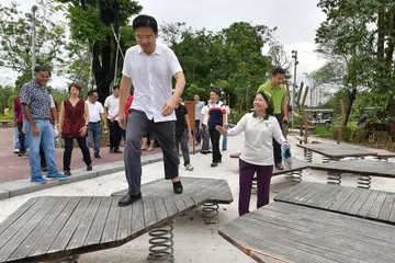 TAMAN BARU: Menteri Pembangunan Negara, Encik Lawrence Wong (depan) meninjau taman permainan, salah satu ciri menarik di Taman Lakeside. - Foto BM oleh NG SOR LUAN