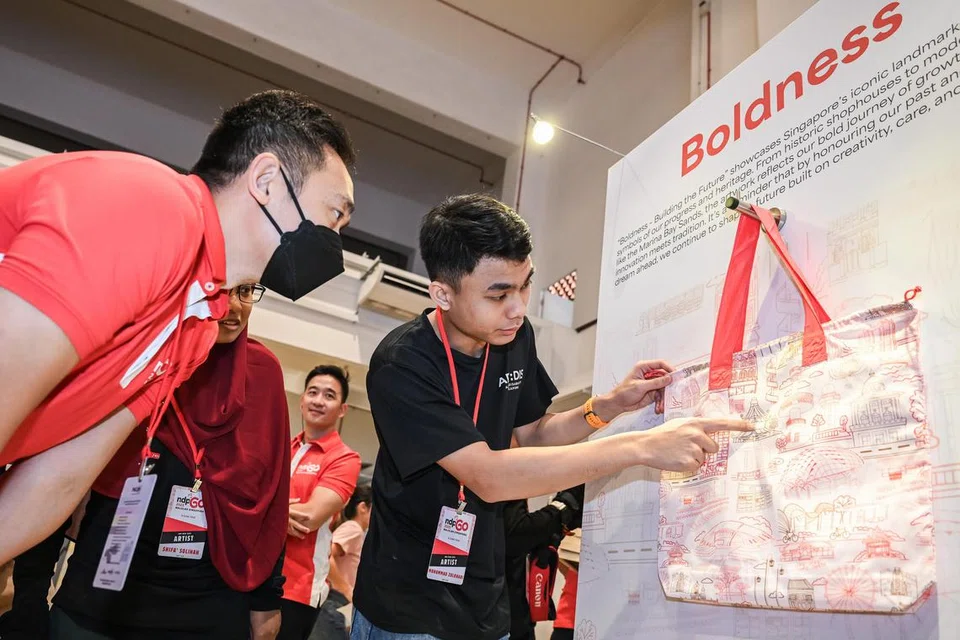 Mohammad Zulkhairi Lutfi Mohd Azam (kanan), 19 tahun, berkongsi rekaan yang dihasilkan bagi pek Perbarisan Hari Kebangsaan (NDP) 2025, iaitu lukisan lima mercu tanda ikonik – Lapangan Terbang Changi, Marina Bay Sands, Pinnacle@Duxton, kuil dan taman permainan naga yang terletak di Toa Payoh. 