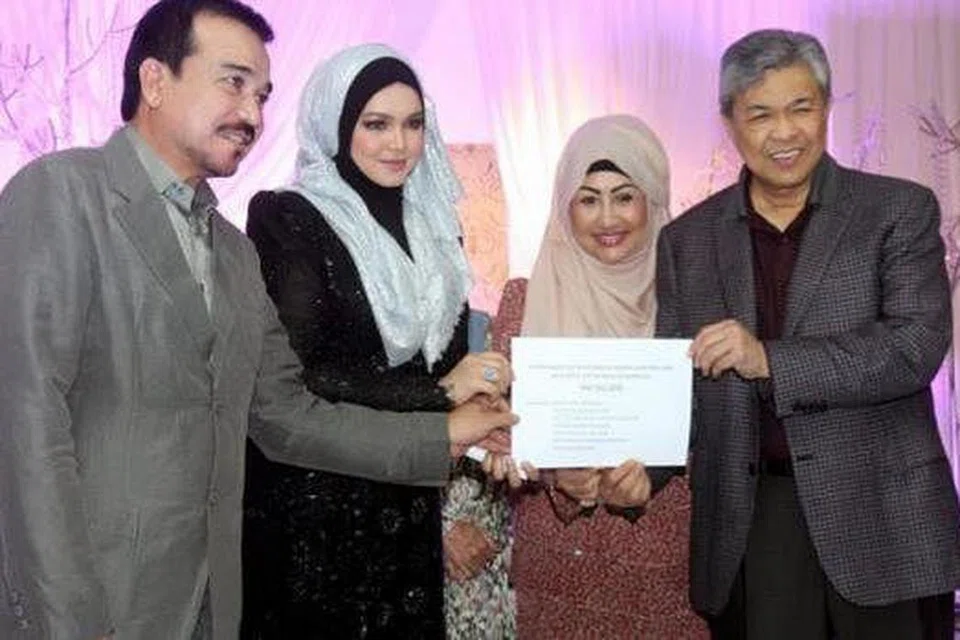 BUAT SUMBANGAN: Datuk Siti Nurhaliza (dua dari kiri) bersama suami, Datuk Seri Khalid Muhammad Jiwa (kiri), menyerahkan sumbangan buat mangsa banjir kepada Menteri Dalam Negeri, Datuk Seri Dr Zahid Hamidi (kanan). - Foto THE STAR