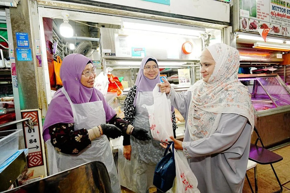 Cik Roslina Onn (kiri) dan kembarnya, Cik Rosliza Onn (tengah), cuba sedaya upaya untuk mengekalkan harga jualan ayam beku dan segar, walaupun mengalamai kenaikan bagi kos.