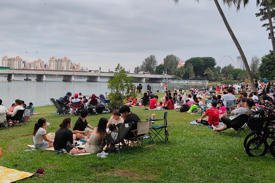 Keluarga berkelah di Kallang Riverside Park sementara menunggu langit menjadi gelap dan pertunjukan bunga api bermula.