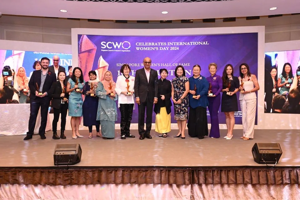 Sekumpulan 10 wanita, termasuk (lima dari kiri) Profesor Madya Emeritus Hadijah Rahmat, disenaraikan dalam Dewan Termasyhur Wanita Singapura, atau Singapore Women’s Hall of Fame (SWHF), pada 2024. Mereka menerima trofi yang digelar Obor, atau The Flame, oleh Presiden Tharman Shanmugaratnam (tengah) di majlis Sambutan Hari Wanita Antarabangsa SCWO dan Majlis Induksi SWHF Ke-10 di The Fullerton Hotel pada 8 Mac.