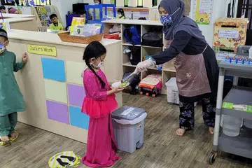 MAKAN DENGAN SELAMAT:Kanak-kanak di prasekolah Kidz Meadow ini harus beratur dengan jarak selamat sebelum mengambil sajian semasa waktu makan. - Foto KIDZ MEADOW