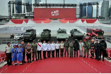 KEMBALI MERIAH: Pegawai dari SAF, SPF dan SCDF, serta wakil daripada kumpulan beruniform sekolah dan pertubuhan sosial dan ekonomi kelihatan bergambar bersama di The Float@Marina Bay, menandakan perbarisan dan pertunjukan lebih besar berbanding tahun-tahun pandemik. - Foto BH oleh GIN TAY