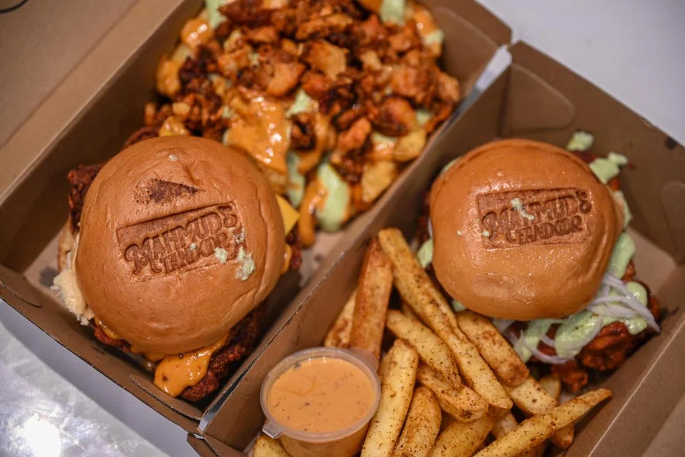 MAHMUD’S TANDOOR: Kotak kiri ialah Crispydoori Burger bersama Loaded Fries ($17) dan kotak kanan ialah OG Baked Tandoori Burger dengan Masala Fries serta sos mayo harissa ($15).