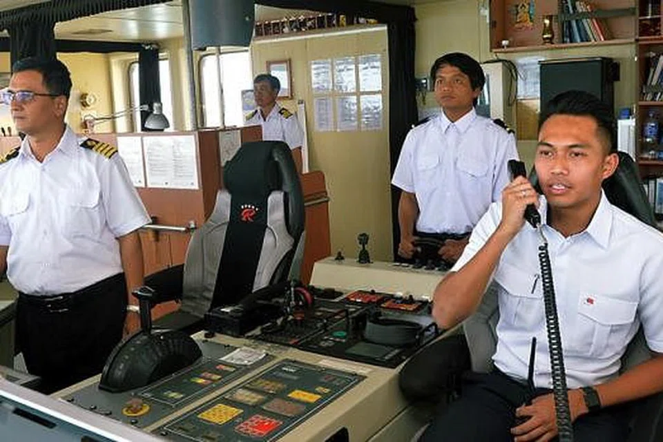 JALANKAN TUGAS DENGAN YAKIN DAN TENANG: Encik Zulhadis (kanan) semasa memberi arahan kepada nakhoda dan kru kapal supaya mereka dapat mengemudi kapal di perairan Singapura dengan baik. 