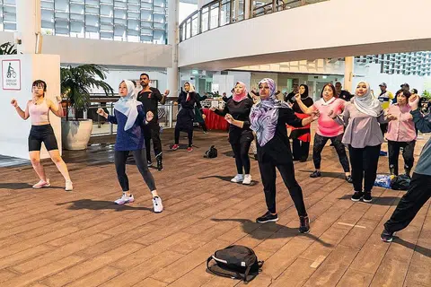 SENANG SENAM: Cik Rahayu (dua dari kiri) menyertai peserta 'Senang Senam' serta anggota keluarga dan rakan mereka semasa acara finale program itu di PAssion WaVe @ Jurong Lake Gardens.