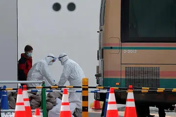 PINDAHKAN PENUMPANG: Pekerja yang mengenakan peralatan perlindungan membantu menaikkan bagasi penumpang ke dalam bas selepas penumpang meninggalkan kapal persiaran Diamond Princess yang berlabuh di Pelabuhan Yokohama, selatan Tokyo, Jepun. - Foto REUTERS