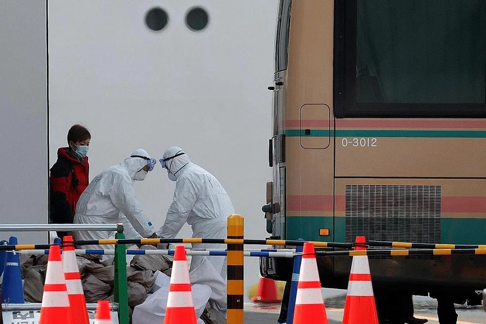 PINDAHKAN PENUMPANG: Pekerja yang mengenakan peralatan perlindungan membantu menaikkan bagasi penumpang ke dalam bas selepas penumpang meninggalkan kapal persiaran Diamond Princess yang berlabuh di Pelabuhan Yokohama, selatan Tokyo, Jepun. - Foto REUTERS