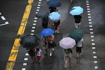 Pejalan kaki melintasi persimpangan jalan di Serangoon Avenue 2 dalam keadaan hujan pada 10 Januari.