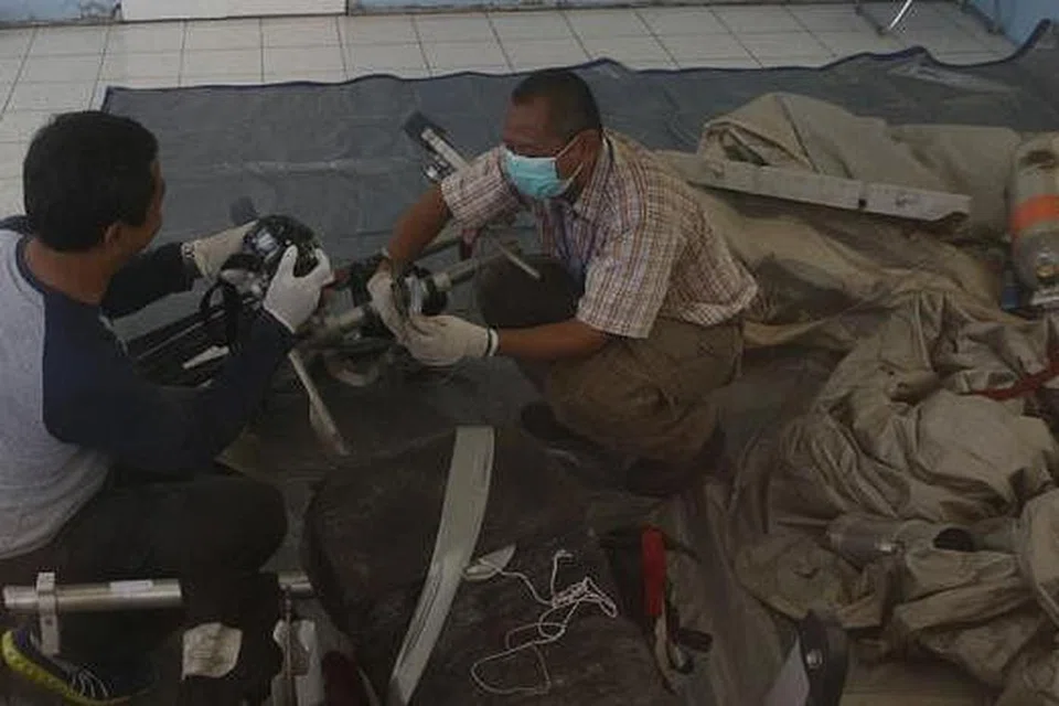 PERIKSA SERPIHAN BANGKAI PESAWAT: Anggota Jawatankuasa Keselamatan Pengangkutan Indonesia memeriksa serpihan bangkai pesawat AirAsia QZ8501 di Pangkalan Bun, Kalimantan Tengah. - Foto REUTERS