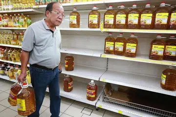 Seorang pembeli membawa dua botol minyak masak di sebuah pasar raya di Malaysia. 