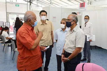 BERAMAH MESRA DENGAN PENDUDUK: Encik Masagos (kanan) bersama Mufti Dr Nazirudin (tengah) dan Encik Esa beramah mesra dengan salah seorang penduduk Tampines, Encik Adnan (berbaju oren) yang telah ke poliklinik Tampines untuk mendapatkan suntikan vaksin Covid-19. - Foto FACEBOOK MASAGOS ZULKIFLI MASAGOS MOHAMAD 