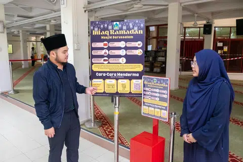 Pegawai Dakwah, Ustaz Hayyan Muhyiddin Kamaruzaman (kiri) dan Pegawai Pemasaran dan Komunikasi, Cik Maisarah Syahirah Malik (kanan) menjelaskan cara-cara anggota jemaah boleh menderma kepada Masjid Darussalam.