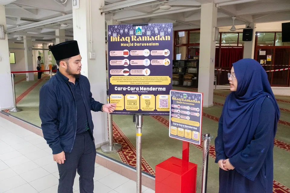 Pegawai Dakwah, Ustaz Hayyan Muhyiddin Kamaruzaman (kiri) dan Pegawai Pemasaran dan Komunikasi, Cik Maisarah Syahirah Malik (kanan) menjelaskan cara-cara anggota jemaah boleh menderma kepada Masjid Darussalam.