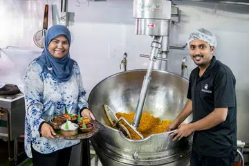 LAUK-PAUK HARI RAYA: Mamanda Catering menyediakan pelbagai lauk Hari Raya sebahagian daripada khidmat katering yang disediakan. Cik Masmunah Abdullah (kiri), pengurus Mamanda Catering ditemani pekerjanya, Encik Ajuman. - Foto BH oleh NUR DIYANA TAHA