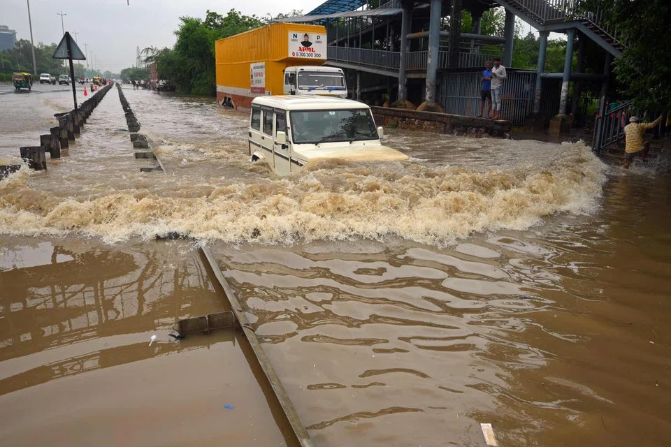 HARUNGI BANJIR: Seorang pengguna memandu kenderaannya di jalan raya yang dinaiki air selepas hujan monsun lebat di Gurgaon di pinggir New Delhi pada Ahad.