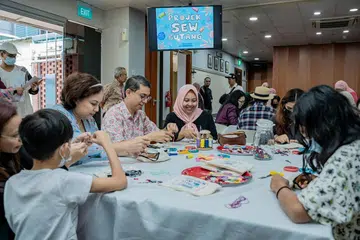 Profesor Faishal Ibrahim bersama Cik Haslinda (bertudung) sedang melakukan kegiatan di acara Projek 'Sew Butang' anjuran Dana Pendidikan Harun Ghani (HGEF) pada hari ini (24 Dis). 