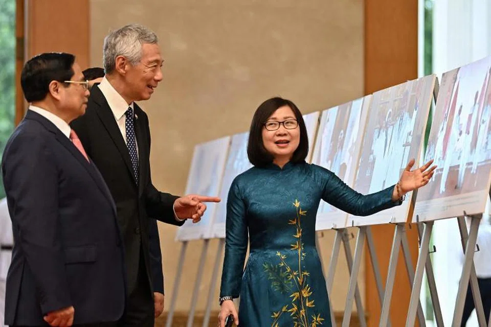 TINJAU PAMERAN: Perdana Menteri, Encik Lee Hsien Loong meninjau dan mendengar taklimat mengenai pameran yang menampilkan gambar-gambar berkaitan hubungan dua hala Singapura dan Vietnam, diiringi  Perdana Menteri Vietnam, Encik Pham Minh Chinh (kiri), sebelum mereka menghadiri satu mesyuarat di Pejabat Pemerintah Hanoi. 