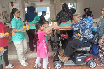 Relawan Project Pencil Singapore mengagihkan buah limau yang diselamatkan daripada dibuang ke tong sampah kepada seorang warga emas. 