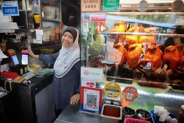 PERNIAGAAN LAMA GUNA TEKNOLOGI BARU: Gerai Putri Hana yang asalnya ditubuhkan lebih empat dekad lalu dan kini dikendali penjaja generasi kedua, Cik Rokiah Hamzah, menawarkan khidmat e-pembayaran melalui kaedah Kod Respons Pantas Singapura (SGQR) sejak tahun lalu. 