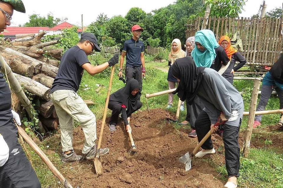 PENUHI KEPERLUAN PENDUDUK KAMPUNG: Seramai 19 sukarelawan, termasuk Cik Nur Atikah dan Cik Siti Nurnajihah, menganjurkan 'Project Giveback' bagi membantu penduduk kampung Treas di Kampong Cham, Kemboja, membina longkang. - Foto THE WIDAAD PROJECT