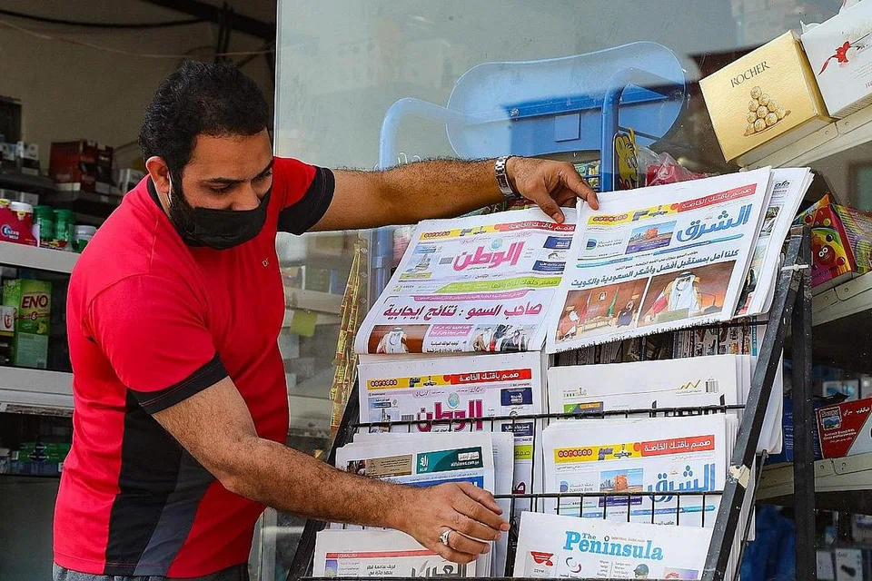 KHABAR GEMBIRA: Seorang lelaki menyusun akhbar yang melaporkan tentang keputusan sidang puncak Majlis Kerjasama Teluk (GCC) menarik balik sekatan ke atas Qatar oleh Arab Saudi, Amiriah Arab Bersatu (UAE), Bahrain dan Mesir sejak Jun 2017. - Foto AFP