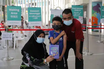 INGIN MELANCONG: Muhammad Rafa Qusyairi Md Rifqi, lapan tahun, meluahkan keghairahan untuk melancong ke Lego Land di Malaysia setelah selesai menerima vaksinasi sepenuhnya. Bersama ke pusat vaksinasi di Kelab Masyarakat Nee Soon East adalah ibu bapanya Cik Norliyana Mustaffa dan Encik Md Rifqi Abdul Jalil. - Foto BH oleh ONG WEE JIN