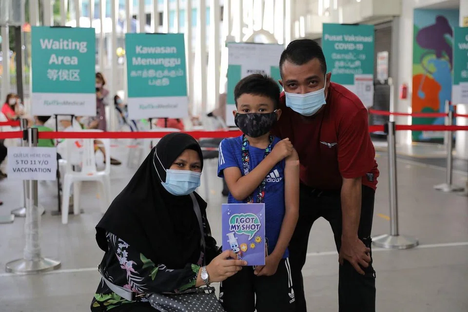INGIN MELANCONG: Muhammad Rafa Qusyairi Md Rifqi, lapan tahun, meluahkan keghairahan untuk melancong ke Lego Land di Malaysia setelah selesai menerima vaksinasi sepenuhnya. Bersama ke pusat vaksinasi di Kelab Masyarakat Nee Soon East adalah ibu bapanya Cik Norliyana Mustaffa dan Encik Md Rifqi Abdul Jalil. - Foto BH oleh ONG WEE JIN