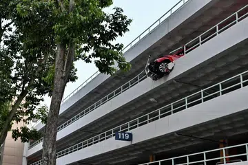 TERGANTUNG KELUAR: Sebahagian depan kereta Volkswagen Beetle ini telah merempuh sebahagian dinding parapet di tingkat empat tempat letak kereta ini.