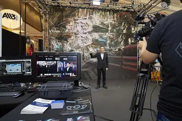 TEKNOLOGI PENGELUARAN VIRTUAL: Menteri Negara Kanan (Pembangunan Negara merangkap Perhubungan dan Penerangan), Encik Tan Kiat How kelihatan sedang membuat 'rakaman' dengan menggunakan teknologi pengeluaran virtual di belakangnya sewaktu pembukaan acara Pasaran dan Forum TV Asia|Skrin Singapura (AFT|SS) semalam. - Foto IMDA