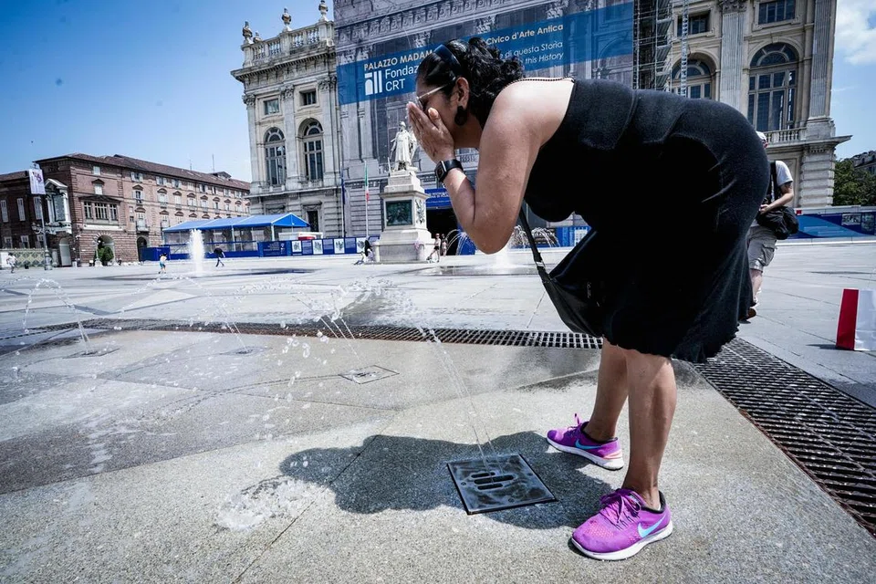 SEJUKKAN BADAN: Wanita ini mengambil kesempatan mencuci muka dengan air pancutan di hadapan Piazza Castello, di Turin, utara Italy. Lapan bandar utama di Italy diisytiharkan sebagai kawasan merah dan gelombang haba ini dijangka berpanjangan selama minggu. 