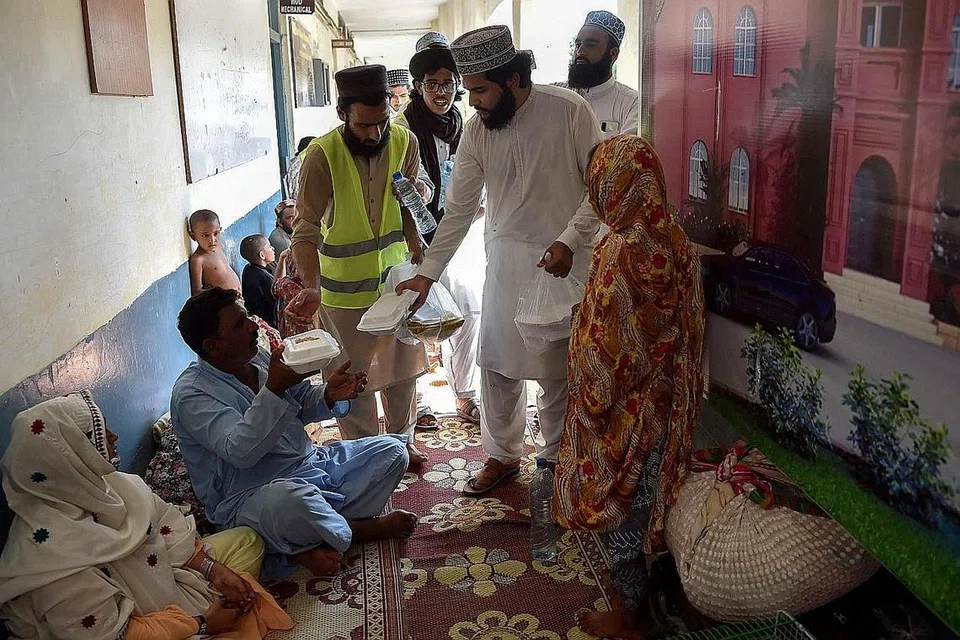 BANTU MANGSA: Pegawai bertugas menghulurkan bungkusan makanan kepada mangsa banjir yang berteduh di khemah sementara di wilayah Khyber Pakhtunkhwa, Pakistan. - Foto AFP