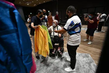 BERSALIN BAJU BARU RAYA TAHUN INI: Encik Mohamed Johari Suraji (berkerusi roda) memilih baju Raya beliau dengan dibantu Profesor Muhammad Faishal Ibrahim (kiri). - Foto BH oleh LIM YAOHUI