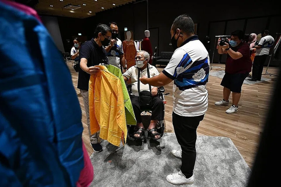 BERSALIN BAJU BARU RAYA TAHUN INI: Encik Mohamed Johari Suraji (berkerusi roda) memilih baju Raya beliau dengan dibantu Profesor Muhammad Faishal Ibrahim (kiri). - Foto BH oleh LIM YAOHUI