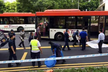 TUTUP MAYAT: Polis menutup mayat seorang warga tua yang meninggal dunia selepas dilanggar sebuah bas di luar pusat pertukaran bas Toa Tayoh pagi semalam. - Foto THE STRAITS TIMES