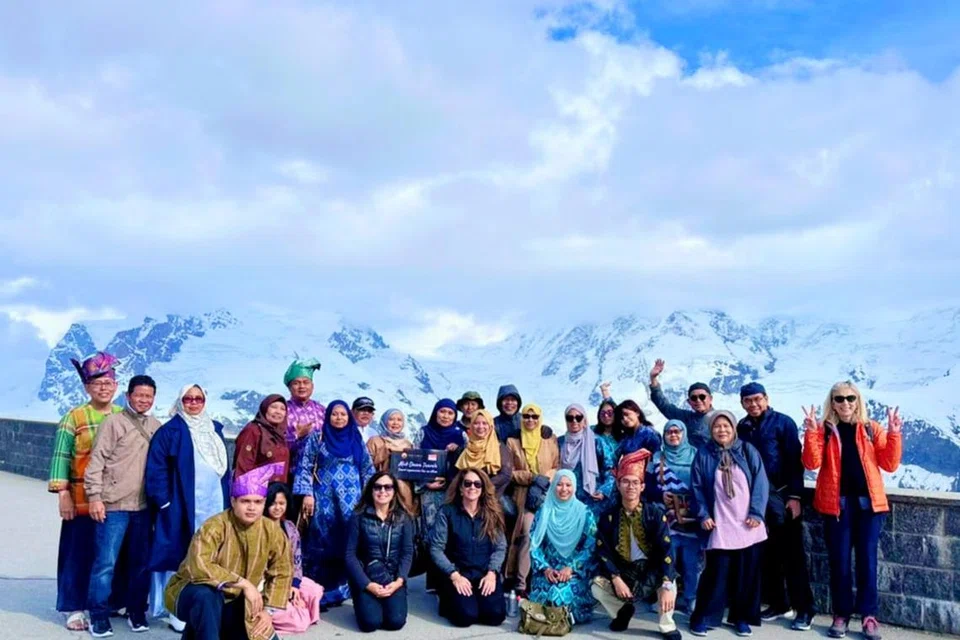 HARI BAJU KURUNG: Pelancong wanita berbaju kurung manakala yang lelaki bertanjak yang dibawa agensi pelancongan Mid-Dawn Travels untuk bergambar di kawasan dingin menghadap gunung-ganang di Gornegrat di Switzerland.