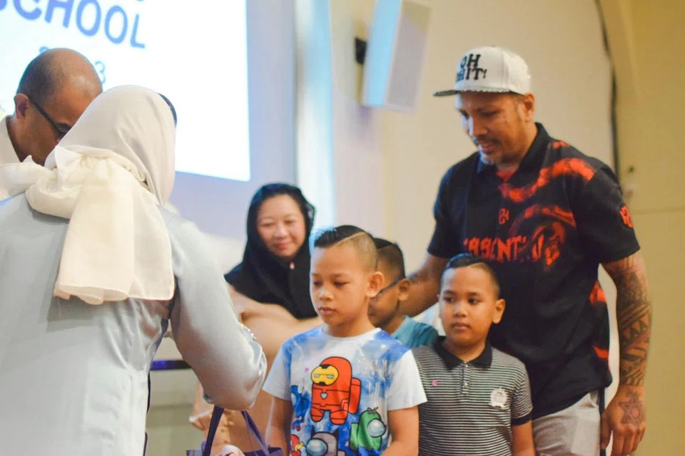 SYUKUR: Encik Mohammad Kamal Abdullah (kanan), 43 tahun, bersama anak-anaknya yang menerima habuan beg sekolah dalam satu acara ‘Kembali Ke Sekolah’ bagi kanak-kanak keluarga berpendapatan rendah di Masjid Al-Islah di Punggol pagi Ahad.
