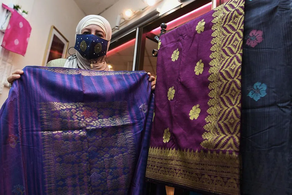 SONGKET MASIH DICARI: Cik Maimunah Ali menunjukkan songket tenun tiga benang sambil menggalakkan masyarakat Melayu supaya terus melestarikan pemakaian busana yang dibuat daripada kain songket. Beliau ditemui di butiknya dalam Pusat Beli-Belah Golden Landmark Rabu lalu.- Foto BM oleh KHALID BABA