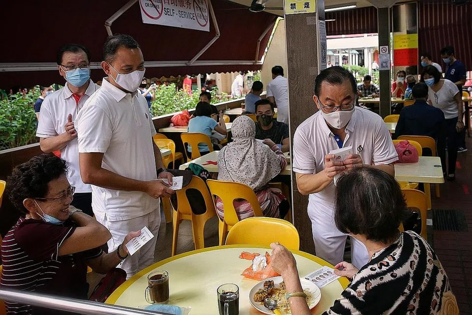 SEBAR PESANAN: Encik Fahmi Aliman (kiri) dan Encik Seah Kian Peng (kanan) yang menganggotai pasukan PAP di GRC Marine Parade memberikan kad kempen kepada penduduk di sebuah kedai kopi di Serangoon Central semalam. Pasukan PAP di sana, yang dipimpin Speaker Parlimen Encik Tan Chuan-Jin, akan bersaing dengan pasukan dari Parti Pekerja (WP) dalam pilihan raya ini. - Foto BH oleh KEVIN LIM