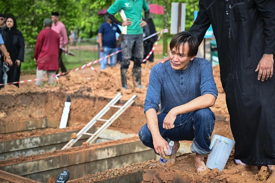 TENUNGAN DUKA: Suami Allahyarhamha Nur Aisyah Md Akbar, Encik Abdul Rauf Mohd Said, kelihatan hiba di sisi kubur arwah isterinya pada 27 Disember sambil ditemani rakannya, Encik Ridhwan Ash-Siddiq.