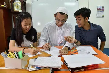 TUISYEN DI MASJID DAN GEREJA: Wynne Choo (kiri) dan Muhammad Khairul Amshar Anuar (kanan) merupakan antara peserta program tuisyen anjuran Masjid Khalid dan Gereja Heart of God. Antara tutor sukarelawan yang membantu menjayakan program tersebut termasuk Encik Amirul Muttaqin Aduka (tengah). - Foto BH oleh Jasmine Choong